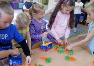 Dzieci na stoliku układają swe papierowe marchewki.